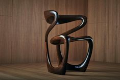 an abstract sculpture sitting on top of a wooden floor next to a wall with wood paneling