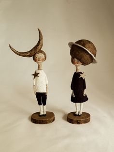 two small figurines are standing on wooden bases