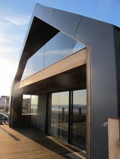 a wooden deck with glass doors on the top and side of a building near water