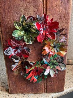 a wooden door with a wreath made out of different types of paper flowers on it