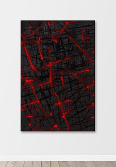 a black and red abstract painting hanging on a wall in an empty room with wood flooring