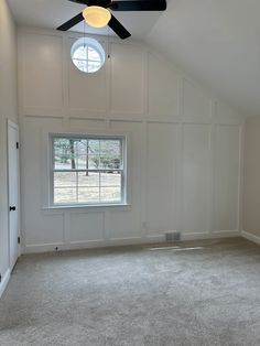 an empty room with a ceiling fan and white paneling on the walls, and carpeted floor