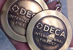 two metal medals are being held in the palm of a person's hand with a keychain