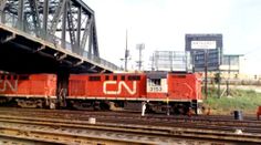 a red train traveling down tracks under a bridge