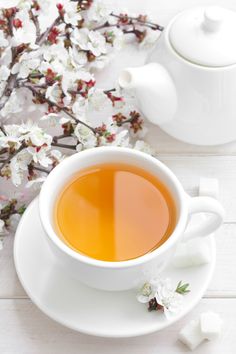 a cup of tea next to some white flowers