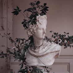 a white marble bust with greenery on it's head