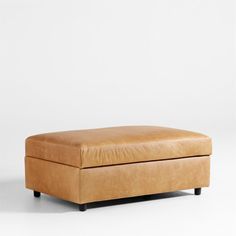 a tan leather ottoman sitting on top of a white floor