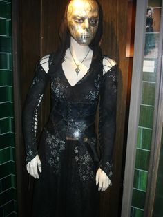 a woman's costume is displayed in a room with green tiles on the walls