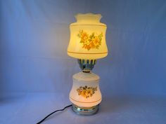 a lamp that is sitting on top of a white base with flowers painted on it