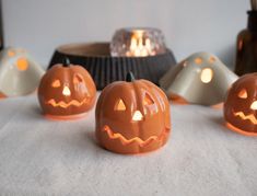 five carved pumpkins sitting on a table next to a candle