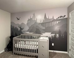 a baby's room with a crib, dresser and wall mural