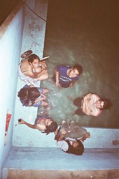 four people are standing in the water at night, with one person taking a photo