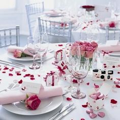 the table is set with pink roses and place settings