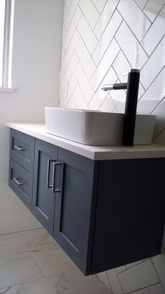 a bathroom with a sink, mirror and tiled wall behind it on the counter top