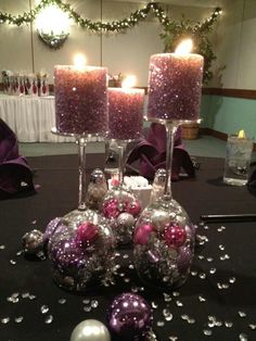 purple and silver ornaments are sitting on a table with candles in the middle, surrounded by other decorations