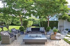 an outdoor living area with couches, chairs and fire pit in the middle of it