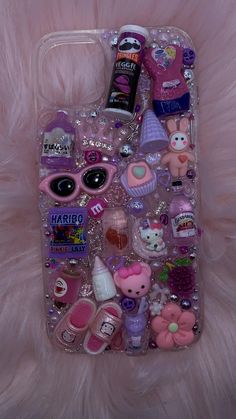 an iphone case with various items on it sitting on a pink furnishing surface