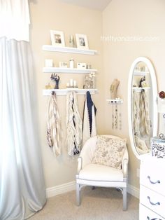 a white chair sitting in front of a mirror next to a wall mounted jewelry rack