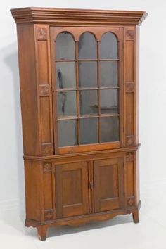 a wooden china cabinet with glass doors on the top and bottom shelves, in an antique style