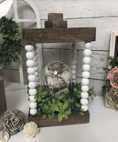 an arrangement of flowers and greenery in a wooden frame on a white table top