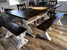 a wooden table with two benches next to it on top of a hard wood floor