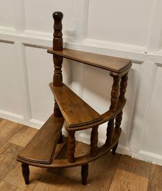 a wooden shelf sitting on top of a hard wood floor next to a white wall