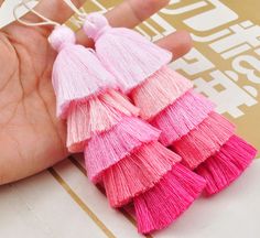 small pink and pink tasselled earrings on a person's hand