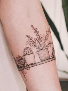 a woman's arm with two potted plants on the left side of her arm