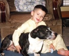 a young boy sitting on the floor next to a dog