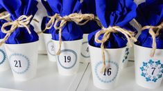 four white cups with blue napkins tied in twine and numbered numbers on them