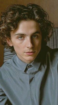 a man with curly hair wearing a blue shirt