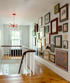 a staircase with many framed pictures on the wall and wood flooring in front of it