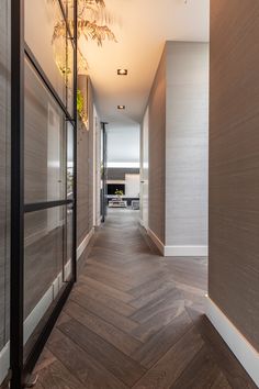 an empty hallway with wood flooring and glass walls