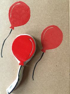 a pair of red balloons on top of a piece of paper with string attached to them