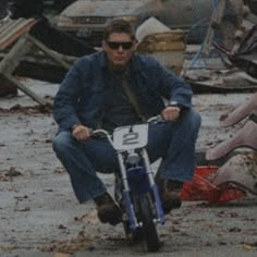 a man riding a motorcycle down a street next to junk