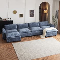 a blue sectional couch sitting on top of a hard wood floor next to a white rug