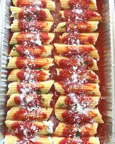 pasta shells covered in sauce and parmesan cheese on a baking sheet with red sauce