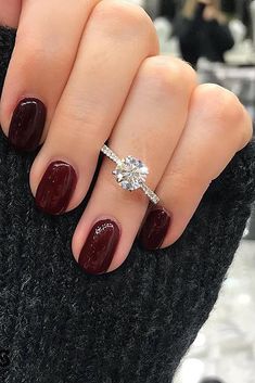 a woman's hand with red nails and a diamond ring on her finger, wearing a black sweater