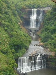 a large waterfall in the middle of a lush green forest