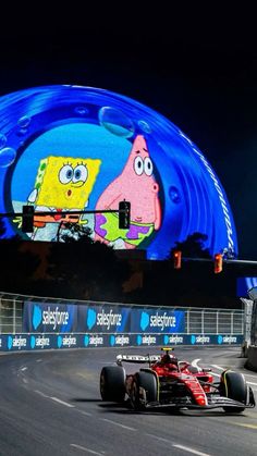 two racing cars driving down a race track at night with cartoon characters on the side