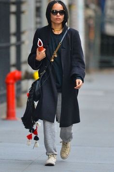 a woman walking down the street with an umbrella in her hand and holding a bag