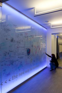 a woman sitting on the floor in front of a glass wall with writing all over it