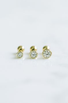 two diamond stud earrings on a white surface