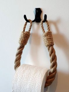 a rope wrapped around a toilet paper roll hanging on a wall with a black hook