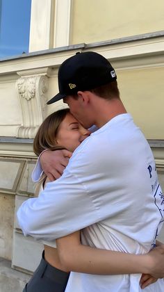 a man and woman embracing each other outside on the street in front of a building