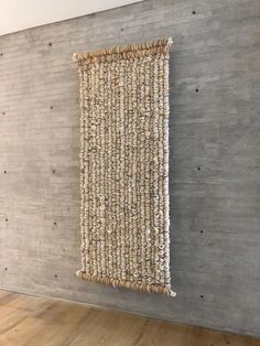 a wall hanging on the side of a wooden floor next to a gray brick wall