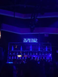 a dark room with blue lights and bottles on the wall