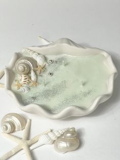 seashells and starfish in a bowl on a white surface with sea shells