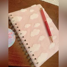 a red pen sitting on top of a pink notebook