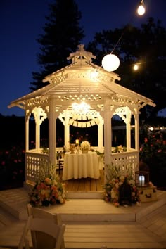 a white gazebo with flowers and lights around it